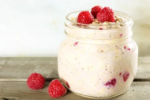 Overnight oats med proteinpulver och hallon i en glasburk, redo för en proteinrik frukost.