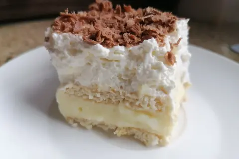 Szybkie ciasto z budyniem i bitą śmietaną, posypane wiórkami czekolady. Idealne na deser!