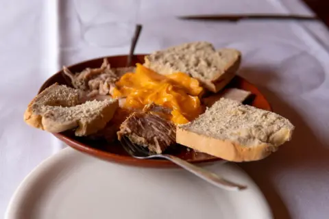 Plato de lomo en manteca con pan rústico y una salsa cremosa de queso.