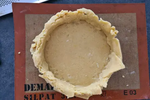 Pâte à gâteau basque prête à être garnie, posée sur un tapis Silpat.