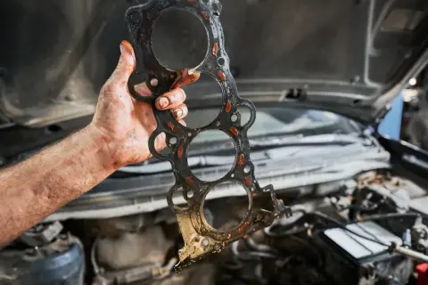 Uszczelka pod głowicą kosztuje sporo, a ta wygląda na zużytą. Mechanik pokazuje ją po demontażu silnika.