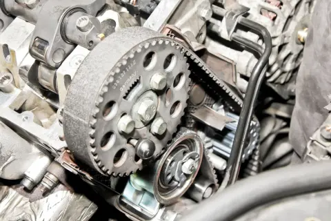 Widok na mechanizm rozrządu w samochodzie: zębatka, pasek i napinacz.