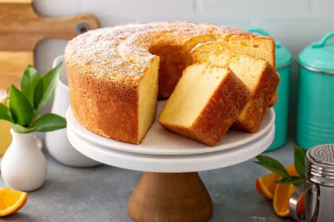 Puszyste ciasto na niedzielę, oprószone cukrem pudrem, z kilkoma kromkami obok. Idealne na rodzinne popołudnie.