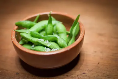 Miseczka pełna zielonej fasolki edamame posypanej solą, gotowa do chrupania.