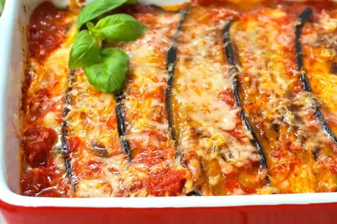 Berenjenas a la parmesana recién horneadas, burbujeantes y doradas, con queso fundido y un toque de albahaca fresca. ¡Un plato italiano irresistible!
