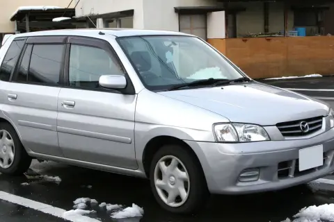 Srebrna Mazda Demio zaparkowana na mokrej nawierzchni ze śniegiem.