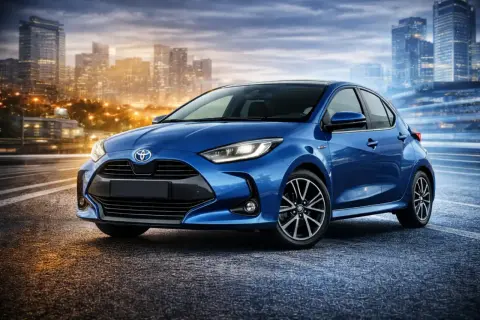 Niebieski Yaris 4 na tle rozświetlonego miasta nocą. Dynamiczna sylwetka i nowoczesne linie podkreślają jego miejski charakter.