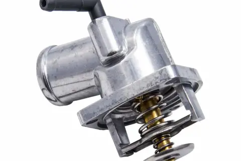 Metalowy termostat w samochodzie z widocznym mechanizmem sprężynowym i czarną złączką.