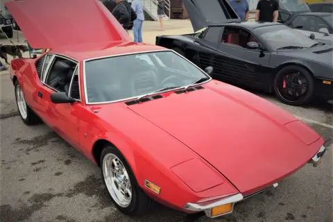 En röd De Tomaso Pantera bil med uppfälld huv. Bredvid står en svart bil med uppfällda dörrar.