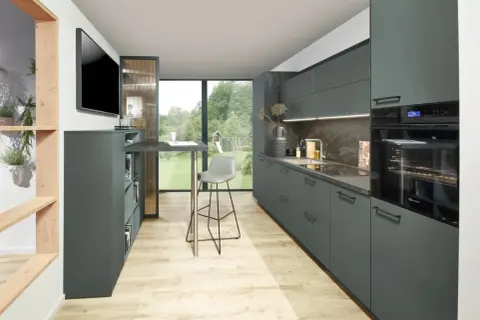 Cocinas modernas con armarios grises, encimera de piedra y suelo de madera clara. Un taburete alto gris junto a una barra.