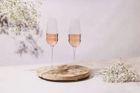 Dwa kieliszki orzeźwiającego wina rose, ozdobione delikatnymi białymi kwiatami, tworzą romantyczną atmosferę.