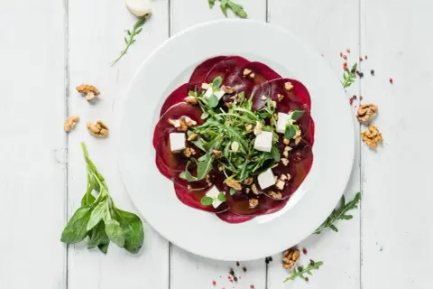 Eleganckie carpaccio z buraka z fetą, orzechami i rukolą. Idealny przepis na lekki i zdrowy posiłek.