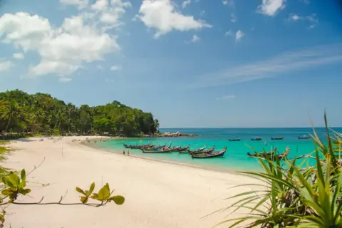 Piękne phuket plaże z turkusową wodą, białym piaskiem i łodziami dryfującymi na morzu.