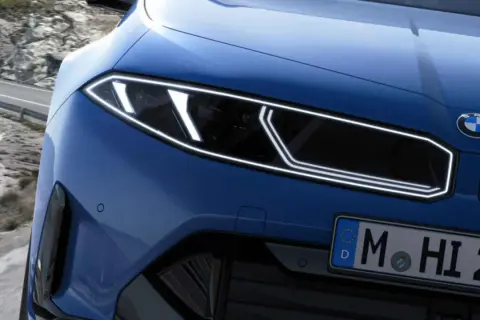 El frontal de un BMW azul eléctrico con tracción trasera, listo para devorar curvas en una carretera de montaña.