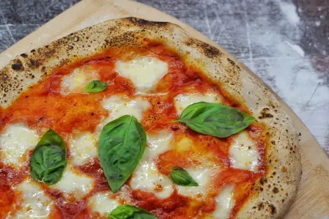 Une Margherita parfaite, symbole de la recette pizza italienne traditionnelle. Sauce tomate, mozzarella fondante et basilic frais sur une pâte dorée.