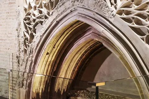 Detalle arquitectónico de un arco gótico en el museo Alma Mater, con ladrillo expuesto y ornamentación de piedra calada.