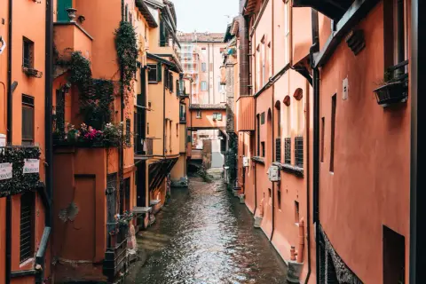 Enge Gasse mit Kanälen und pastellfarbenen Häusern in Bologna. Wie viele Tage würde man hier verbringen wollen?