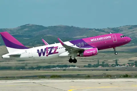 Dwa samoloty Wizz Air z różowymi i fioletowymi elementami startują na tle wzgórz.