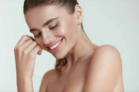 Donna sorridente con pelle luminosa, un esempio di come mantenere la pelle giovane e radiosa.