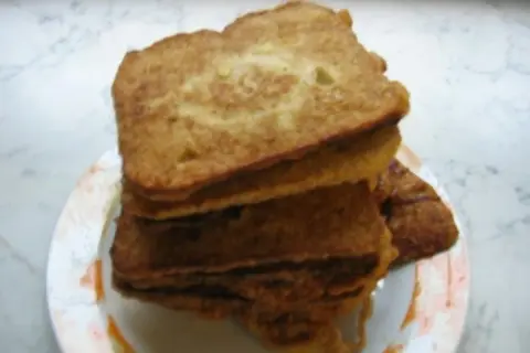 Ein Stapel goldbraunes Brot mit Ei, auf einem Teller angerichtet. Perfekt für ein herzhaftes Frühstück.