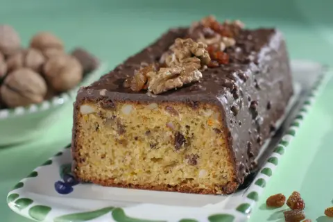 Pyszna babka z orzechami włoskimi, oblana czekoladą i ozdobiona bakaliami.