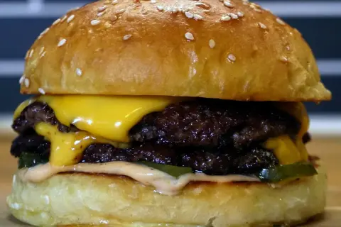En saftig smashed burger med dubbla köttpuckar, smält ost, pickles och dressing. Perfekt för en hungrig dag!