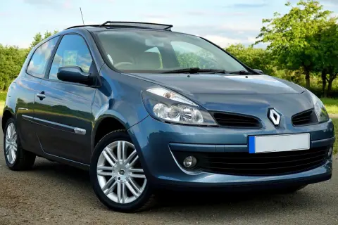 Un Renault Clio azul aparcado en un camino rural. El coche tiene un techo solar y llantas plateadas.