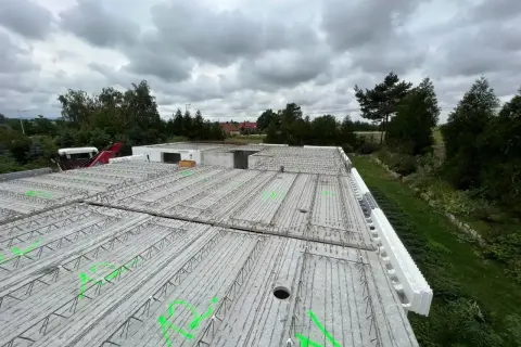 Gotowy do zalania strop żelbetowy, zbrojenie czeka na beton. W tle drzewa i pochmurne niebo.