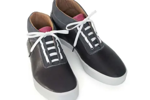 Scarpe sportive nere con lacci bianchi e dettagli grigi. Un esempio di come i lacci scarpe modi possano trasformare un look classico.