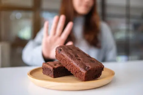 Kobieta odrzuca brownie, wybierając dietę bez cukru.