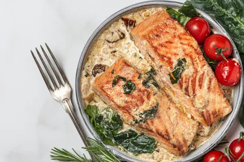 Deux pavés de saumon grillé dans une sauce crémeuse aux épinards, accompagnés de tomates cerises. Une recette saumon parfaite pour un dîner savoureux.