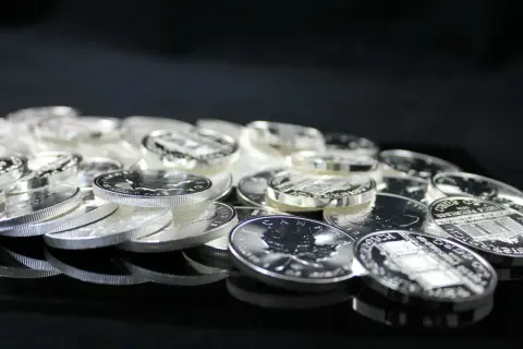 Stos monet ze srebra, błyszczące w świetle. Widać na nich detale, jak liść klonu i budynki. To inwestycja, która może być opodatkowana, czyli vat na srebro.