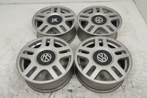 Cztery srebrne felgi aluminiowe Volkswagen z czarnym środkiem i logo VW.