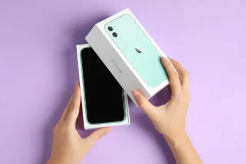 Ręce rozpakowują zielony iPhone 11. Aparat tego modelu pozwala uchwycić każdy piksel z niezwykłą precyzją.