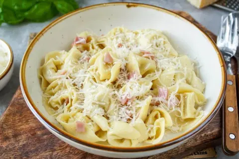 Schon gewusst? Tortellini einfrieren ist eine tolle Idee, um sie später zu genießen. Hier sind sie mit Schinken und Parmesan serviert.