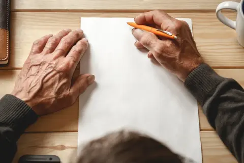 Ręce piszą testament. Zastanawiasz się, ile kosztuje testament notarialny?