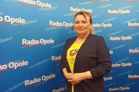 Kobieta w żółtej bluzce i granatowej marynarce na tle z logo Radia Opole.