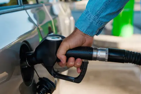 Dłoń trzymająca pistolet paliwowy przy samochodzie. Czas na zimowe paliwo od kiedy? Przygotuj auto na mrozy.