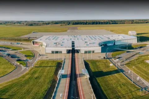 Nowoczesny terminal lotniska w Lublinie, otoczony polami i parkingami.