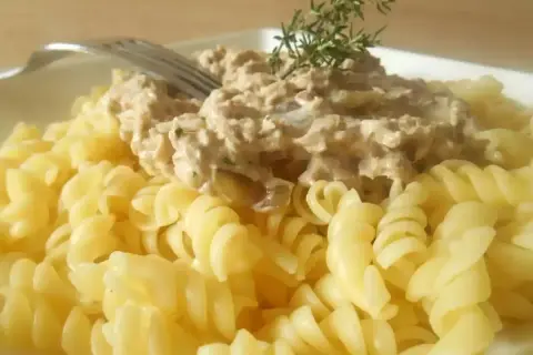 Pâtes fusilli généreusement garnies d'une sauce crémeuse aux pâtes au thon, décorées d'une branche de thym.