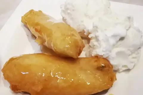 Två gyllene friterade bananer med honung serveras med en generös klick vaniljglass. En ljuvlig dessert!