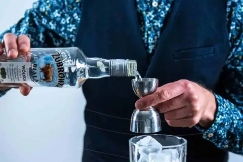 Barman nalewa Żubrówkę do jiggera, przygotowując drinka. Wódki w Polsce to tradycja.