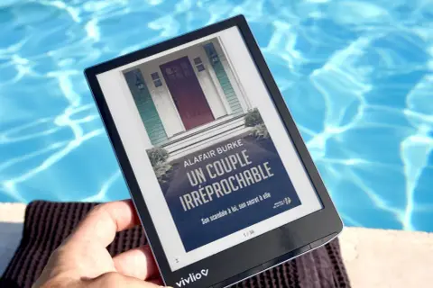 Une liseuse e-ink affiche "Un couple irréprochable" au bord d'une piscine.