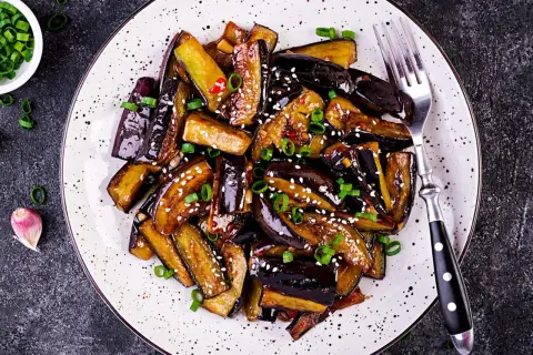 Aubergines laquées, parsemées de sésame et d'oignons verts. Une recette savoureuse pour sublimer ce légume.