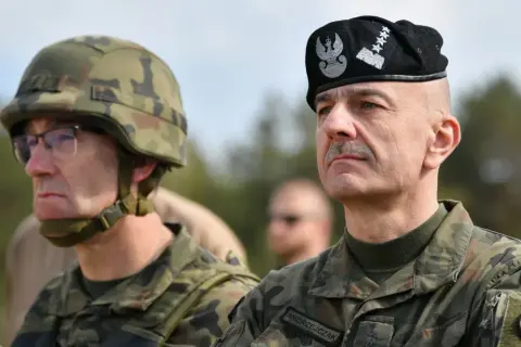 Generał Andrzejczak w czapce z orłem i gwiazdkami, obok żołnierz w hełmie.