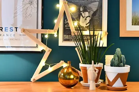 Étoile en bois faite maison, décorée de guirlandes lumineuses. Une décoration simple pour fabriquer une étoile en bois.