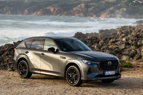 Szary SUV Mazda CX-60 na tle skalistego wybrzeża. To jeden z rodzajów hybryd, który łączy moc z ekologią.
