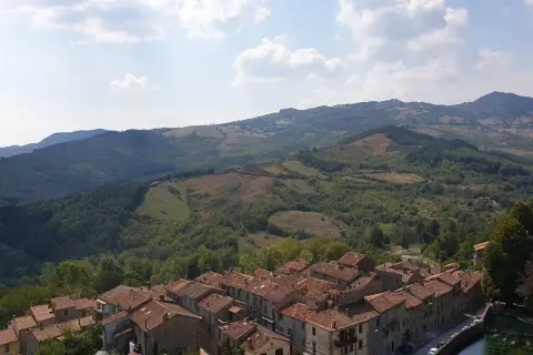 Panoramica di un borgo con tetti in cotto e colline verdi. Un assaggio di cosa vedere sul Monte Amiata, tra natura e storia.