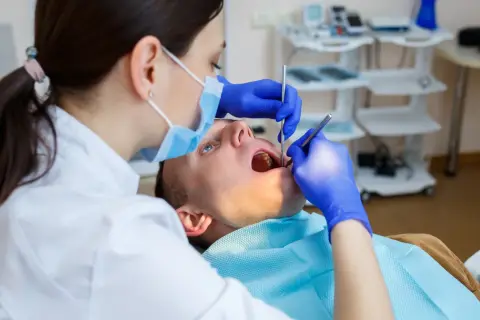 Dentystka bada zęby pacjenta. Czy dentysta może wystawić L4? Tak, jeśli stan zdrowia pacjenta tego wymaga.