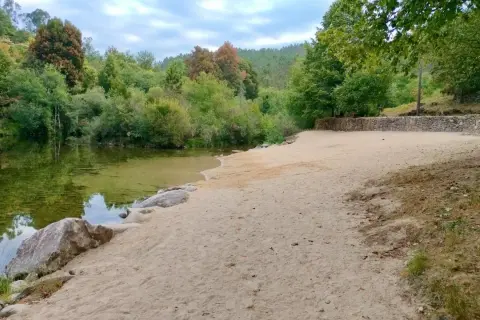 Tranquila playa fluvial en Fornelos de Montes, con arena dorada, aguas cristalinas y rodeada de exuberante vegetación.